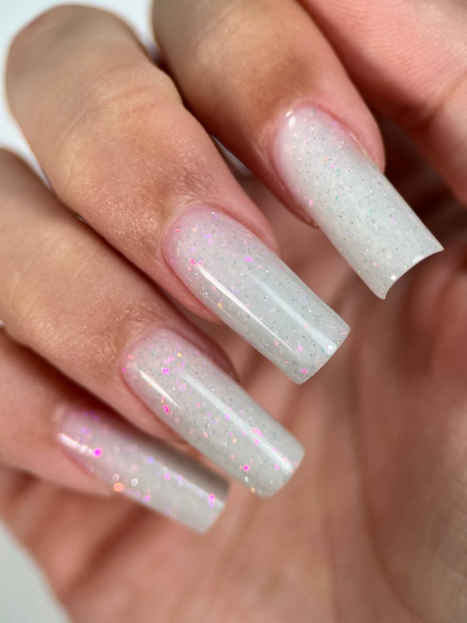 Close-up of Liquid PolyGel #1 bottle with Milky and White Holographic Sparkles.Long nails