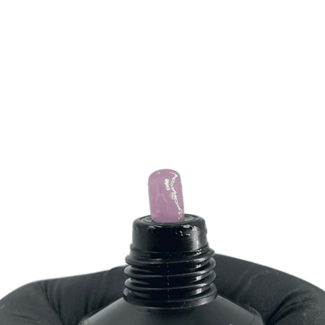  The tube from the first image with a small amount of polygel squeezed out, showing a pastel pink color with a glittery texture, held by a person in black gloves against a white background.