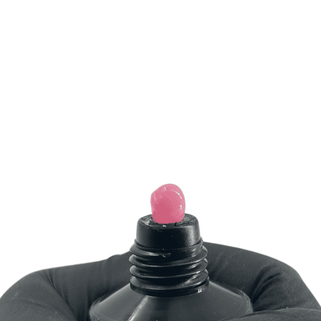 The top of a black tube with a dab of pink polygel emerging from it, ready for nail application. The gel's color suggests a vibrant pink shade for nail enhancement.