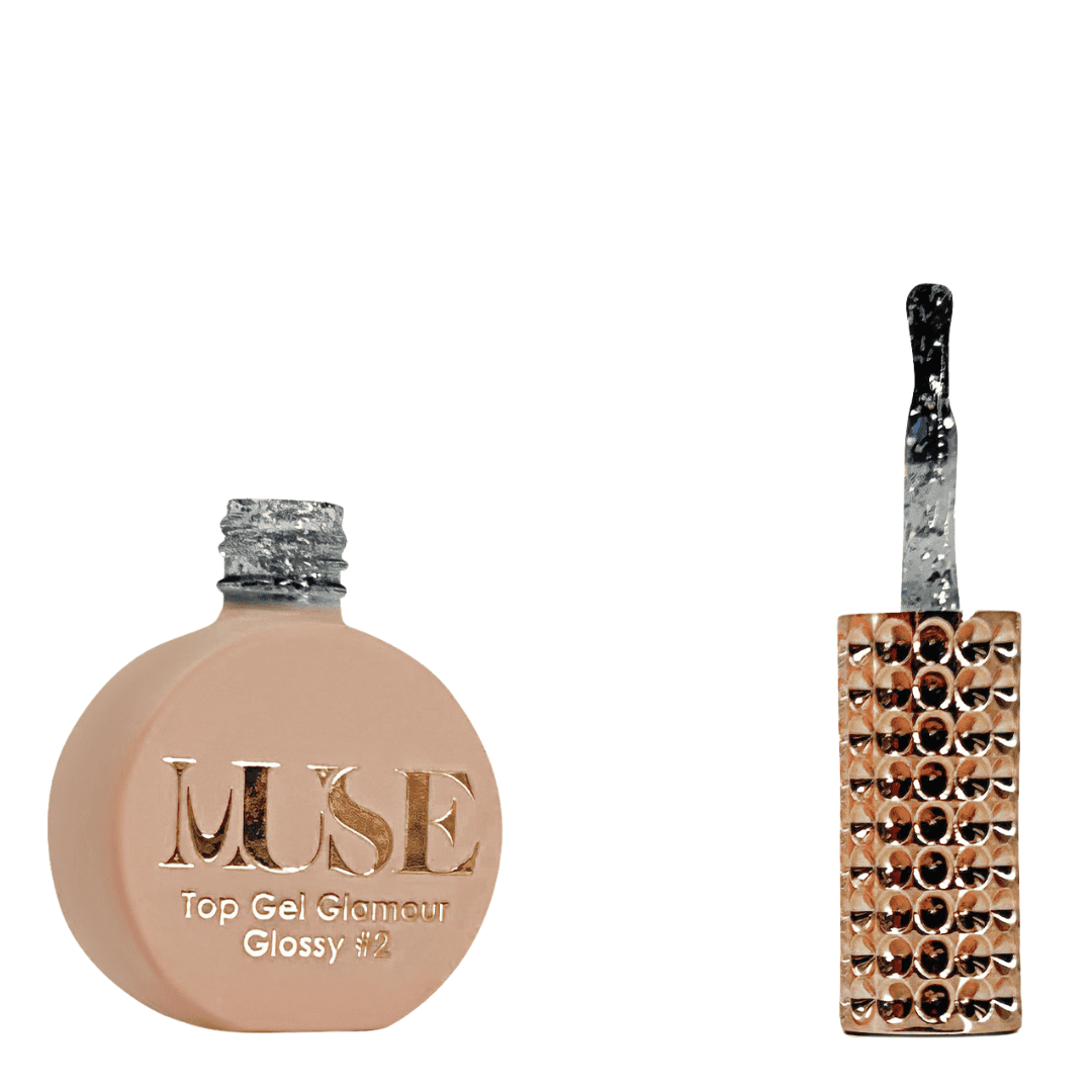 A bottle of MUSE Top Gel Glamour in Glossy #2, featuring a flat, round container with a matte peach finish. The silver screw cap is textured, and the brush applicator has a clear handle filled with sparkling glitter. The label on the bottle displays the MUSE logo in luxurious gold lettering with "Top Gel Glamour Glossy #2" detailed below.