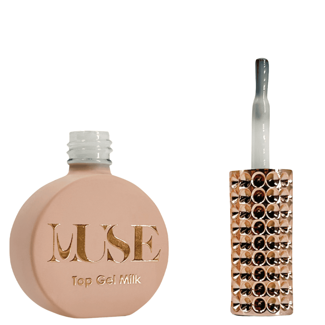 A bottle of MUSE Top Gel labeled "Milk", featuring a flat, circular base with a matte peach exterior. The cap is a clear, silver glitter screw top, and the brush applicator has a clear handle filled with glitter. The label on the bottle is adorned with the MUSE logo in gold lettering, with "Top Gel Milk" indicated below.