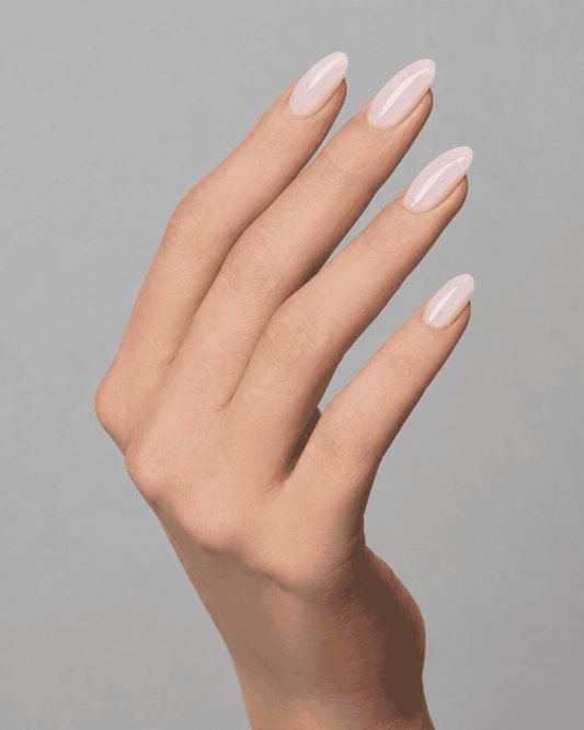 Close-up of elegant almond-shaped nails finished in a soft pink nude liquid polygel shade with a glossy finish. Natural-looking manicure photographed against a light grey background, showcasing smooth coverage and a clean professional nail design by Muse Gel.
