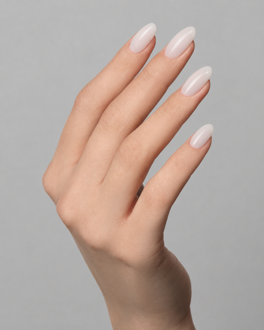 Close-up of elegant almond-shaped nails finished in a glossy milky white gel polish, photographed on a hand against a soft light grey background. Clean, natural manicure with a smooth, semi-sheer finish by Muse Gel.